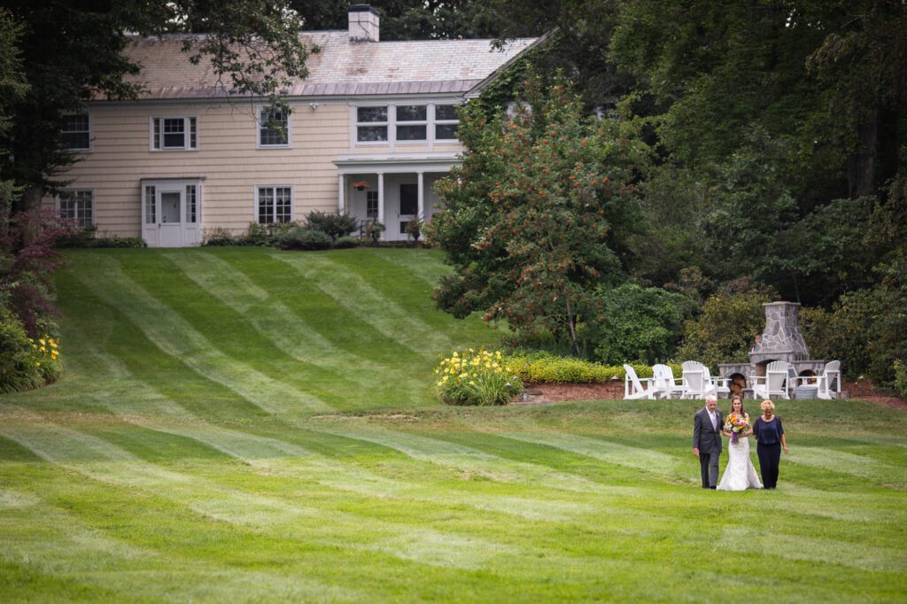 bride-escorted-by-parents-across-lawn-oakholm-farm