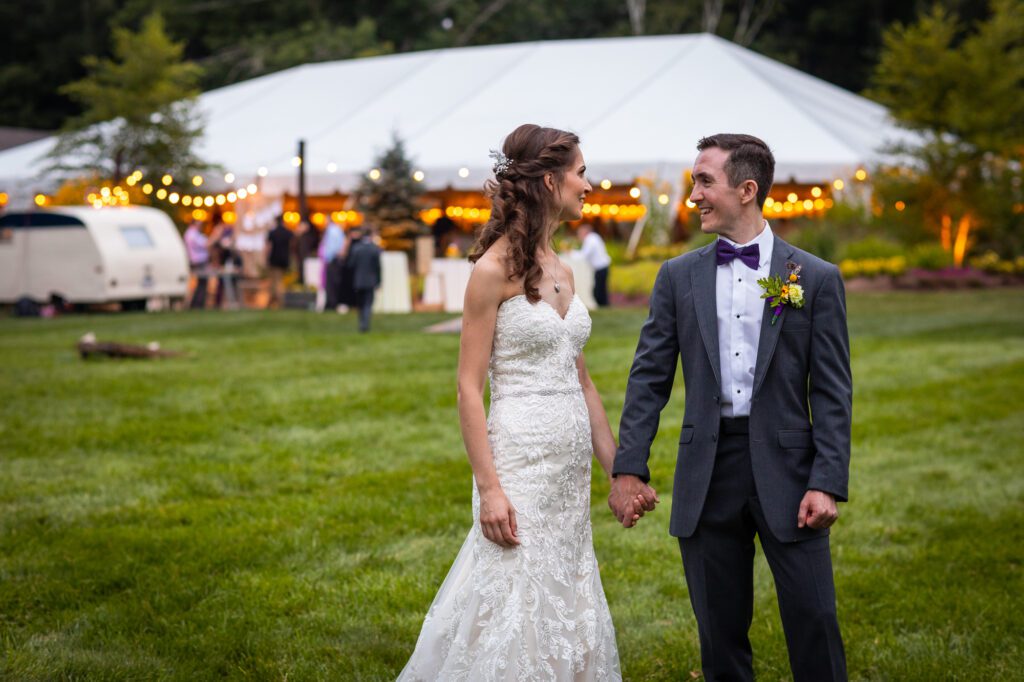 couple-holding-hands-tent-reception-in-background-oakholm-farm
