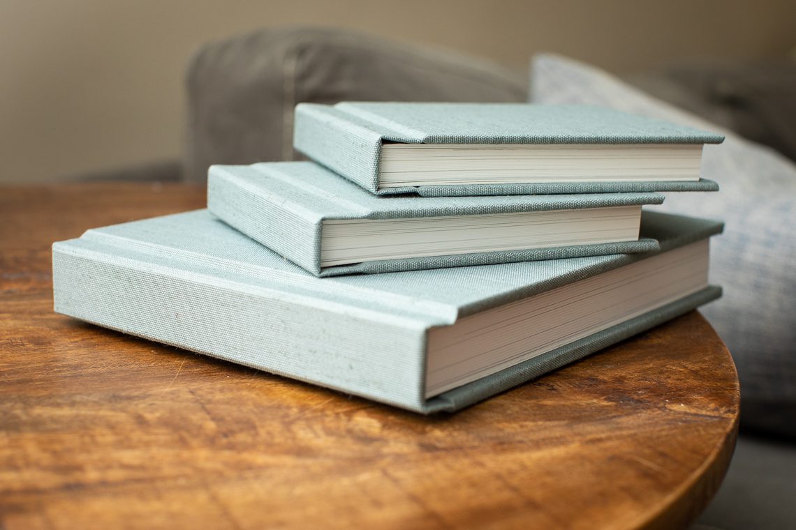 stack-of-three-wedding-albums-with-light-blue-linen-covers-central-mass-wedding-photographer