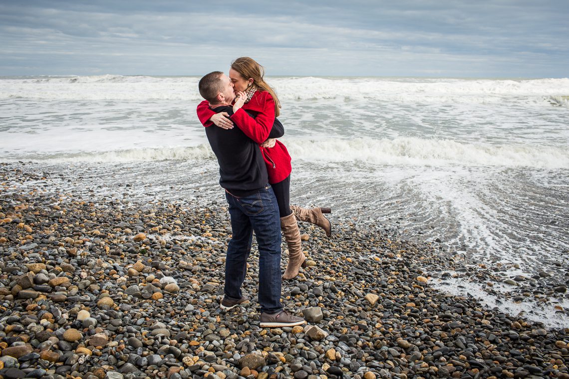 couple-kissing-in-front-of-crashing-waves-winter-beach-engagement-photos-ideas