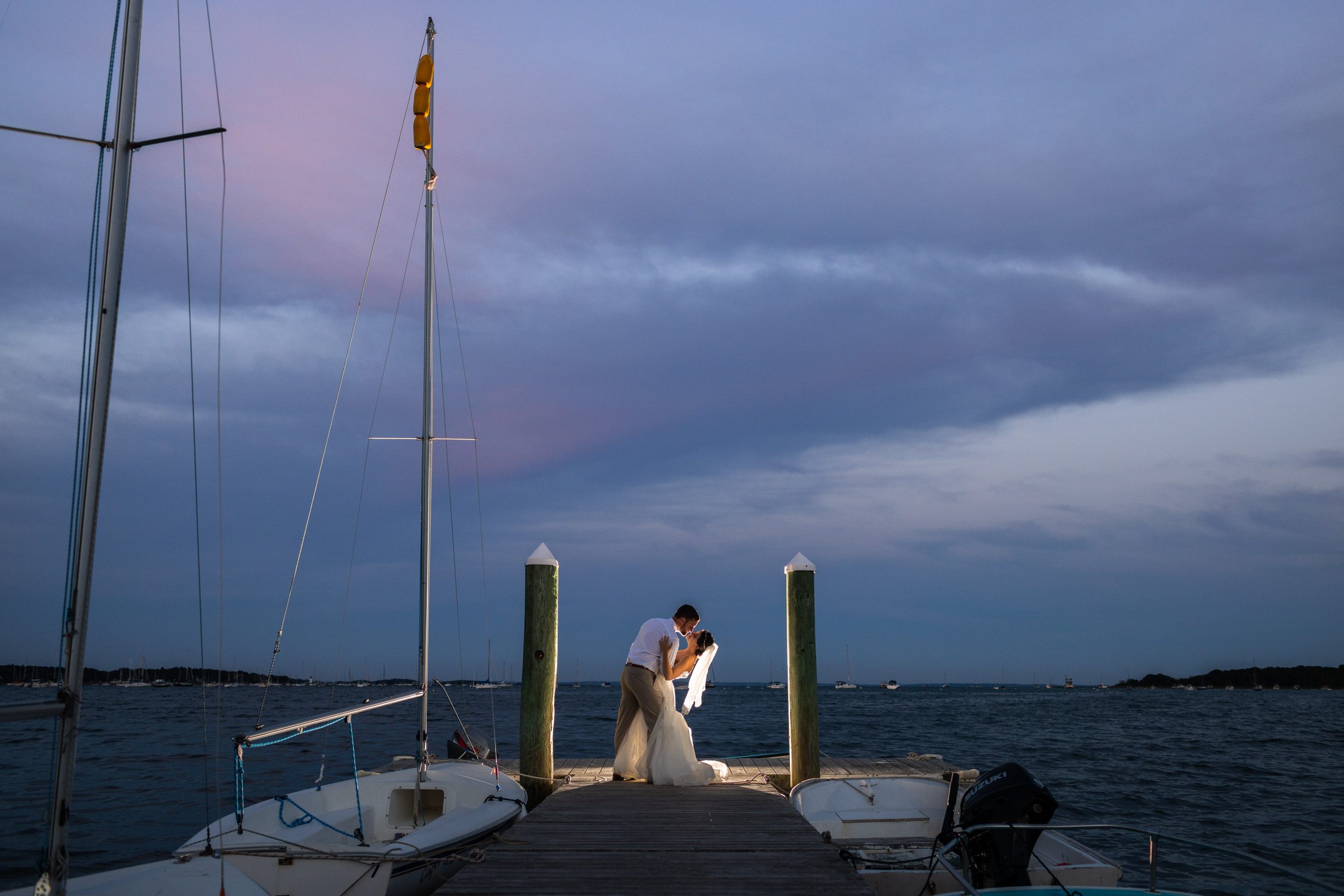 epic-wedding-photos-at-sunset-couple-backlit-on-dock-at-dusk