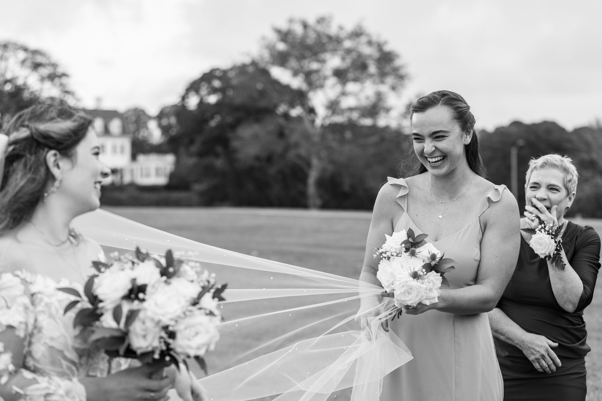 How to find the Perfect Wedding Photographer Bridesmaid helping bride with her veil. Mom looks on smiling big.